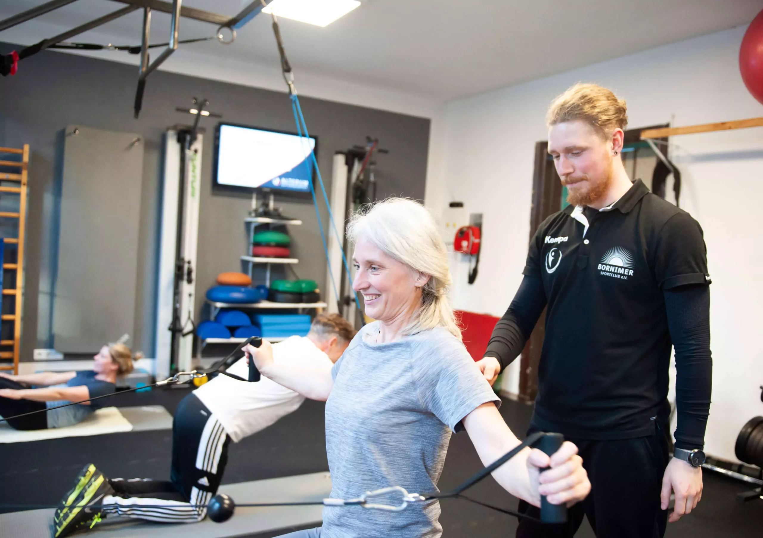 Sporttherapeut betreut eine Patientin beim Seilzugtraining – ALTERUM im Gesundheitspark Bornim